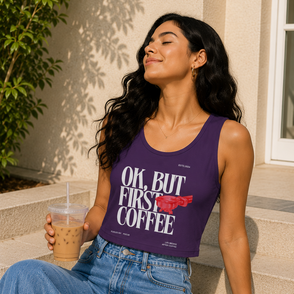 Woman wearing a purple tank top with text, sitting outdoors holding an iced coffee.