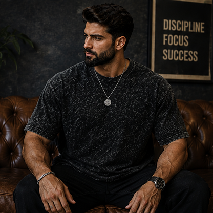 Man sitting on a leather couch wearing a dark t-shirt with motivational quote in the background